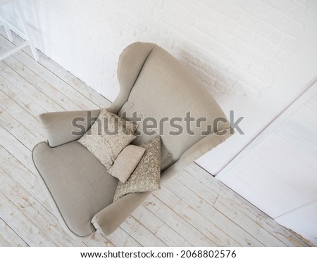 Top view of biege cozy armchair with pillow in room. Minimalist interior concept.
