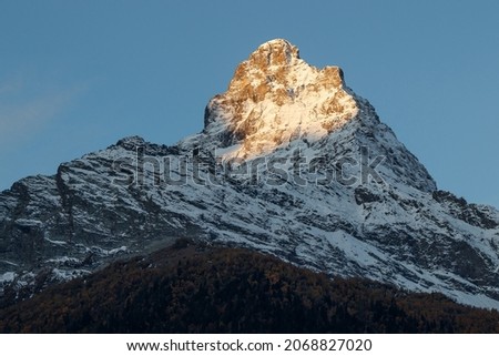 View of Mount Belalakaya illuminated by the setting sun against the background of blue sky, Dombai, Russia.