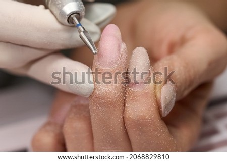 Woman doing manicure for herself with the nail drill. High quality photo
