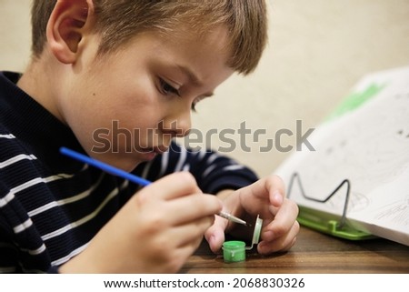 Little boy draws a brush and paint his first picture. Children's leisure at home