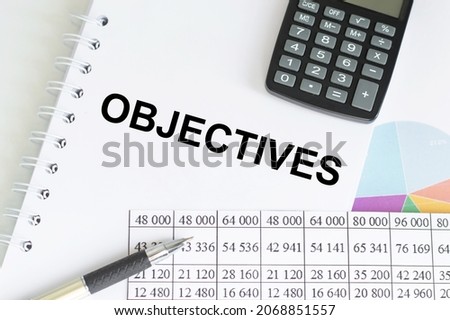 Paper with text objective on the table next to a calculator, a pen and financial reports