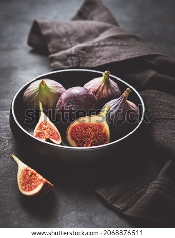 Fresh ripe figs in a black bowl on a dark gray background close-up. Dark and mood concept. Tint image.
