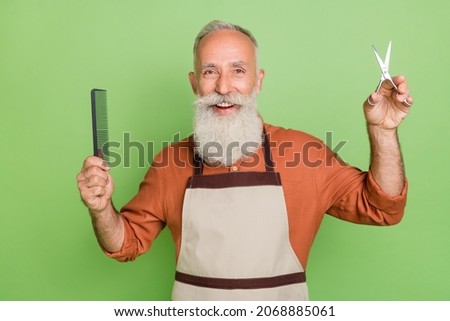 Photo of attractive senior worker hold hairdo cutting tools scissors comb hair stylist isolated over green color background