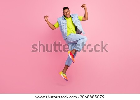 Full body photo of impressed millennial guy jump yell wear vest t-shirt jeans sneakers isolated on pink background