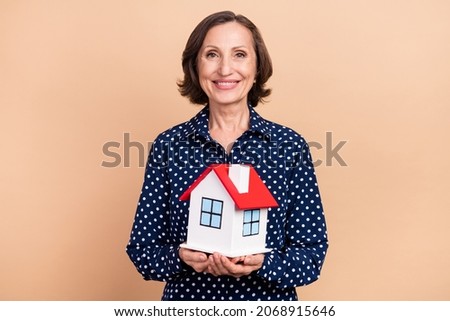 Photo of good elder agent lady hold house wear blue shirt isolated on beige color background