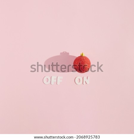 Creative arrangement made of red Christmas bauble and off on words on a pink background. Minimal New Year concept. Turn on Christmas inspiration.
