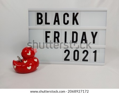 Light box with the text: "Black Friday 2021". On the side a red money box duck with a penny