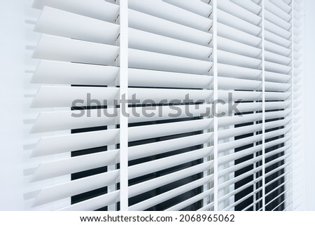 Adjusting vertical or venetian blinds. Design for adjust, close or open by cellular horizontal slate, panel, track or shutter to allow natural light, sunlight or sunshine to inside room or office. Royalty-Free Stock Photo #2068965062