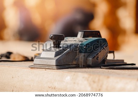 Industrial work carpenter grinds log with electric jointer, construction frame building site of house made of wood. Royalty-Free Stock Photo #2068974776