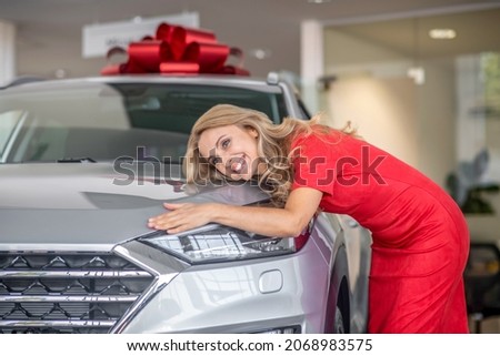 Pretty happy woman touching donated car