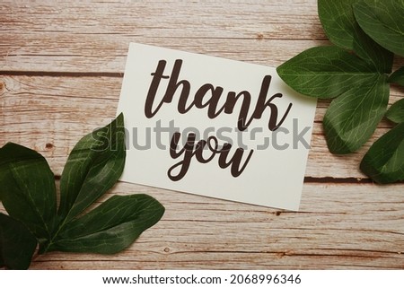Thank You typography text with green leave decorated on wooden background