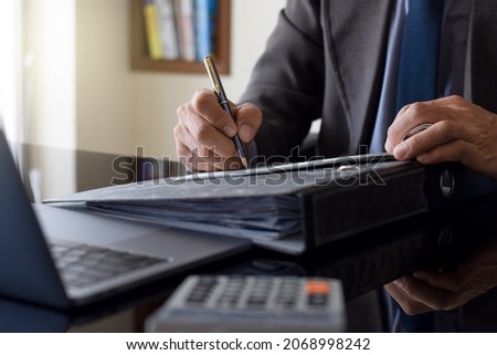 Business man hand writing and signing cheque with laptop computer and calculator on the desk at office. Check payment, paycheck and payroll concept. 