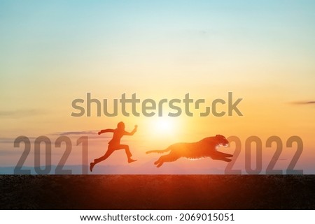 2022 New Year concept. Silhouettes of running man and tiger.