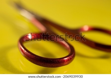 Tools, red scissors for manicure on a yellow background, top view. Nail tool, macro photography