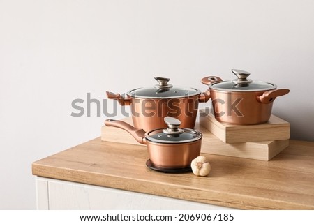 Set of copper cooking pots with garlic on counter near light wall Royalty-Free Stock Photo #2069067185