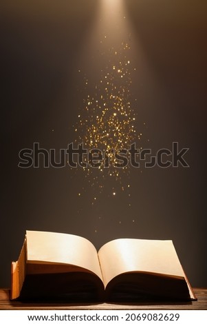 Open old book on table against dark background