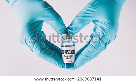 The shape of heart made from hands in gloves holding the covid vaccine booster shot Royalty-Free Stock Photo #2069087141