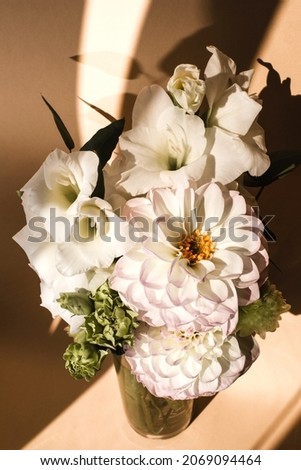 A bouquet of delicate light flowers in a glass vase with a shadow. Flat lay