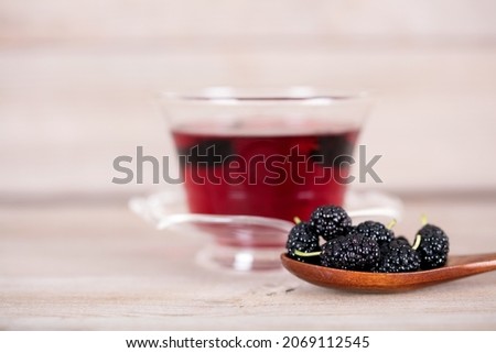 A spoonful of fresh mulberries and brewed mulberry tea
