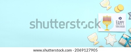 Tasty cookies and greeting card for Hanukkah on color background with space for text