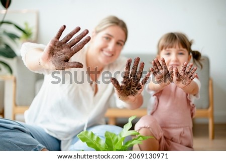 Playful mom and kid potting plant at home Royalty-Free Stock Photo #2069130971