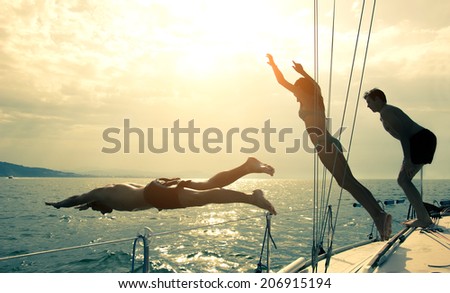 Silhouettes of children diving from the bow of a boat Royalty-Free Stock Photo #206915194