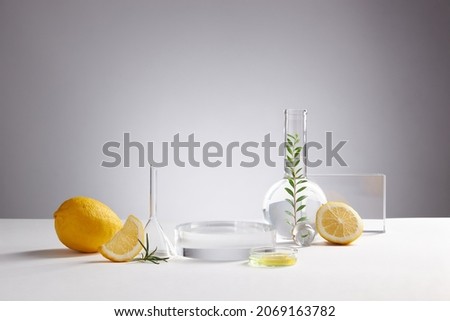 Lemon juice with sliced lemon transparent podium , petri dish in a white background , green leaf in a test tube for advertising , photography food concept