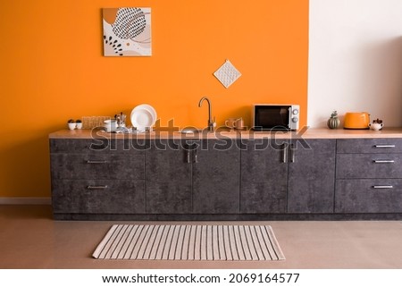 Stylish interior of kitchen with orange wall Royalty-Free Stock Photo #2069164577