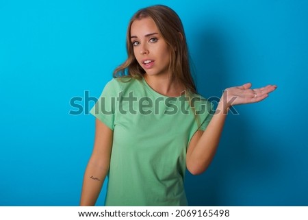 Beautiful caucasian girl wearing green T-shirt over isolated background smiling cheerful presenting and pointing with palm of hand looking at the camera.