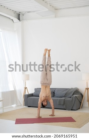 acrobatics handstand exercises cardio warm-up, healthy lifestyle home workout. strong hardy athletic man doing sports fitness gymnastics, brunette