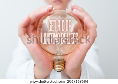 Text caption presenting Get Rid Of Limiting Beliefs. Business showcase remove negative beliefs and think positively Lady in outfit holding lamp with two hands presenting new technology ideas Royalty-Free Stock Photo #2069169584