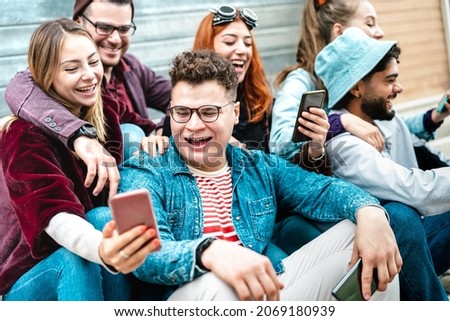 Young milenial friends having fun with mobile phone at campus college yard - Joyful men and women spending time together watching funny viral smartphone video - Bright filter with focus on central guy Royalty-Free Stock Photo #2069180939