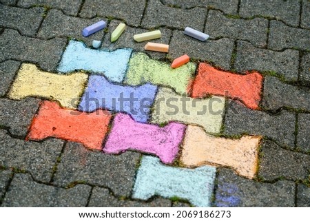 Figures painting with colorful chalks on ground on backyard. Children activity, drawing and creating pictures. Creative outdoors activity in summer.