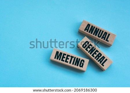 On a bright blue background, light wooden blocks and cubes with the text AGM Annual General Meeting. Royalty-Free Stock Photo #2069186300