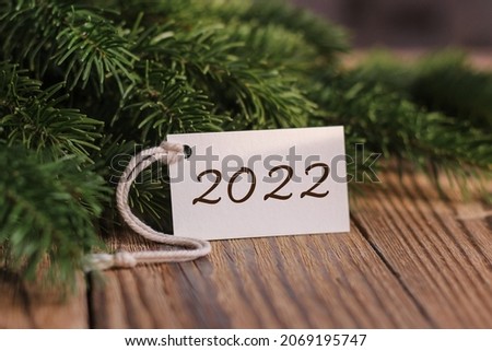 New Year 2022. Fir branches and a tag with the text 2022. New years card