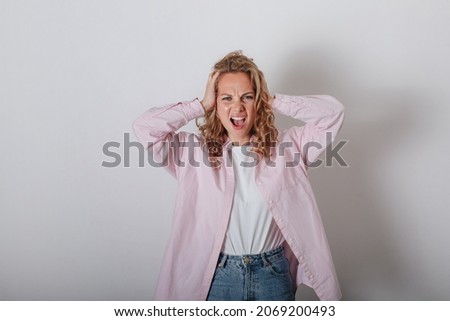 A girl with a headache, holding her head with her hands and screaming