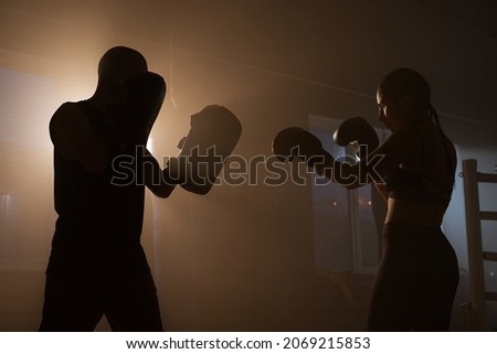 Young Woman Athlete in Boxing Gloves and Sport Clothes is Boxing With her Skillful Trainer. They Dodging Punches While Practicing on Boxing Ring Royalty-Free Stock Photo #2069215853