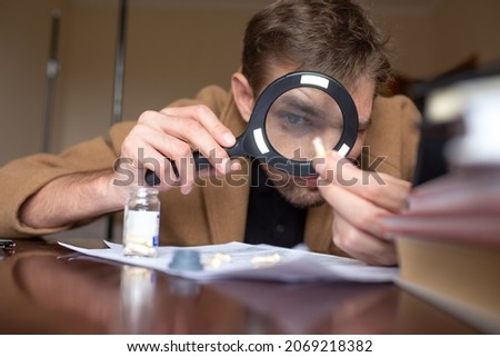 the investigator examines the evidence through a magnifying glass.