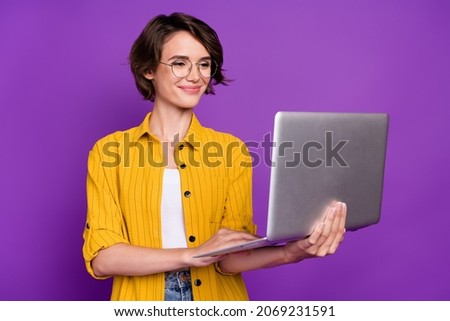 Portrait of attractive cheery focused girl using laptop e commerce chat isolated over bright violet purple color background