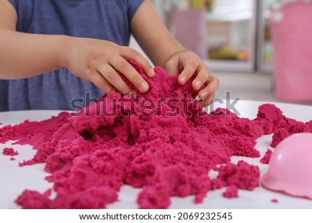 Little girl playing with bright kinetic sand at table indoors, closeup Royalty-Free Stock Photo #2069232545