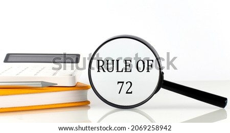 Magnifier with text RULE OF 72 with notebook, calculator on the white background Royalty-Free Stock Photo #2069258942