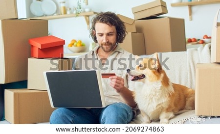 A Man Uses a Laptop For Online Shopping at Home. Purchase Confirmation by the Internet. Binding a Card for Online Shopping. A Man Sitting on the Couch With a Cute Dog While Online Shopping.