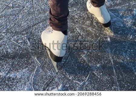 To skate on the ice of a river or lake in winter, white skates slide on the ice in close-up. Royalty-Free Stock Photo #2069288456