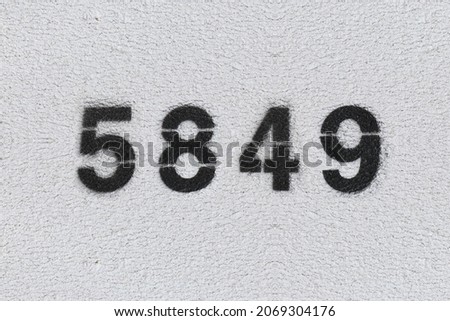 Black Number 5849 on the white wall. Spray paint. Number five thousand eight hundred forty nine.