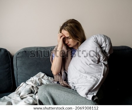 young woman with long covid syndrome - painful condition, headache, sitting on the couch at home Royalty-Free Stock Photo #2069308112