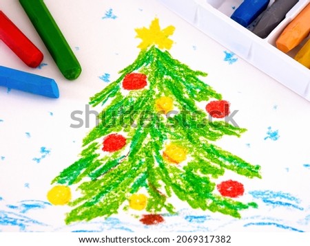 Decorated Christmas tree in snow. A hand drawing oil pastel painting with some oil pastels near it.