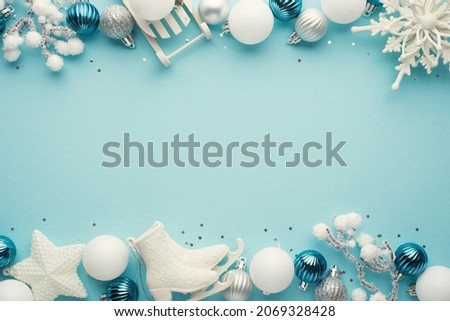 Top view photo of white blue and silver christmas tree decorations snowflake stars balls sequins ice skates sled and snowy branches on isolated pastel blue background with copyspace