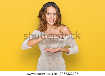 Beautiful young caucasian woman wearing casual clothes gesturing with hands showing big and large size sign, measure symbol. smiling looking at the camera. measuring concept. 