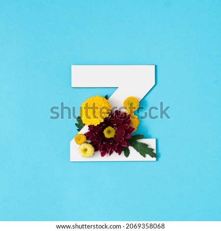 Big white Letter Z made of real natural flowers and leaves on blue background. Flower font concept. Unique collection of letters. 