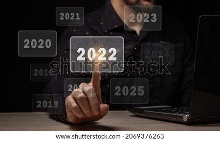 Choosing the new fiscal year 2022. The male hand chooses the new 2022 year. Choosing a new year and new business goals